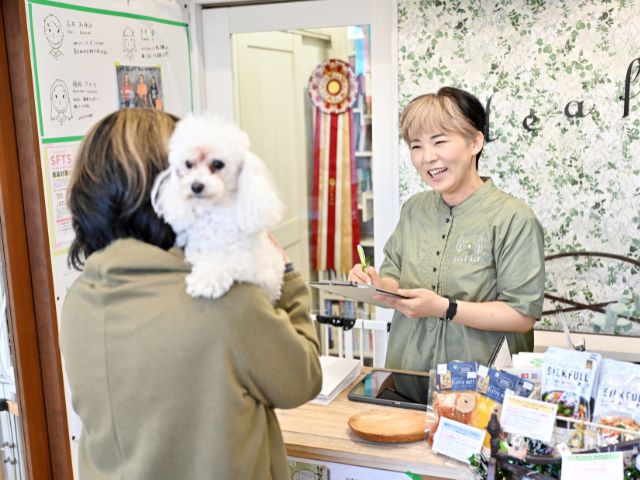 トリマーが笑顔で飼い主にわんちゃんにの様子を伝えている
